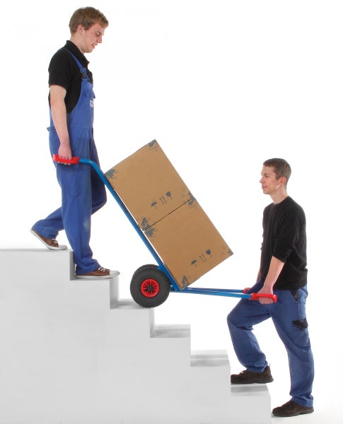 Zwei Männer transportieren einen Karton mit einer Treppenkarre über Treppen.