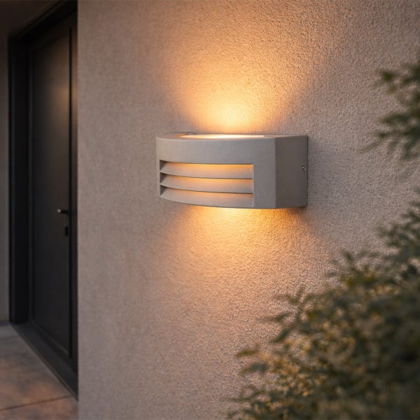 Moderne Außenwandleuchte mit horizontalen Lamellen an einer strukturierten Wand mit Lichtaustritt nach oben und unten.
