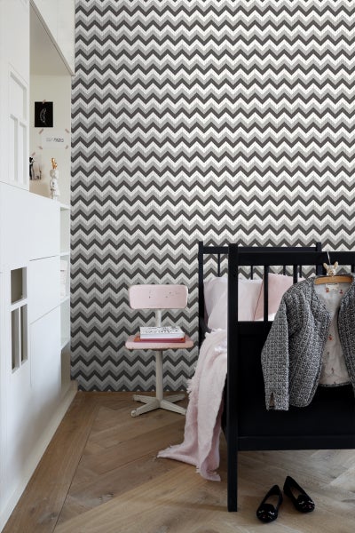 Kinderzimmer mit Zickzack-Tapete, Bett und Stuhl.