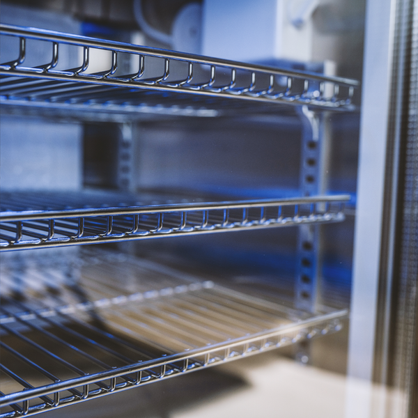 Innenansicht eines Kühlschranks mit verstellbaren Gitterrosten aus Metall.