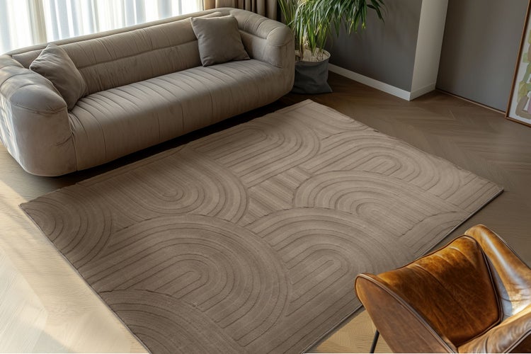 Wohnzimmer mit modernem Teppich mit Reliefmuster, Sofa und Sessel auf Parkettboden.