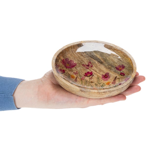 Hand hält eine runde Mangoholzschale mit Blumenmuster