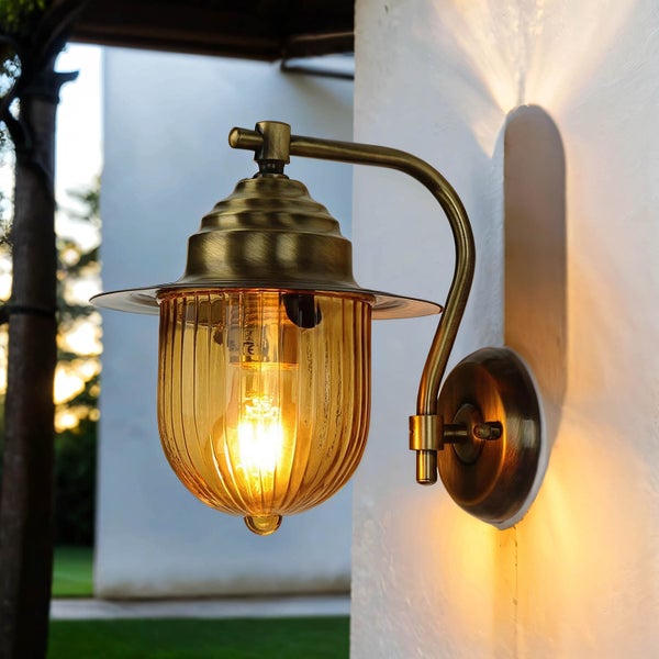 Goldfarbene Außenwandleuchte mit klarem Lampenschirm für den Außenbereich.