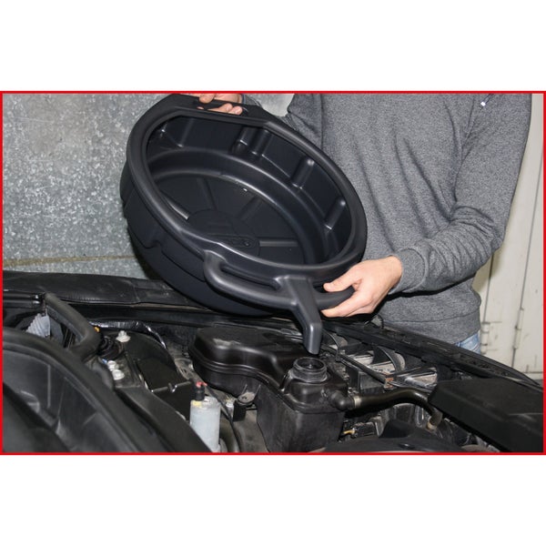 Eine Person verwendet einen schwarzen Ölablassbehälter mit Ausguss zum Einfüllen von Flüssigkeiten in den Ausgleichsbehälter eines Fahrzeugmotors.