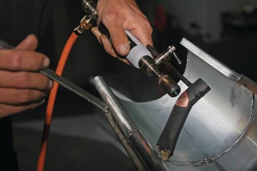 Eine Person schweißt ein Metallstück mit einem Schweißgerät.