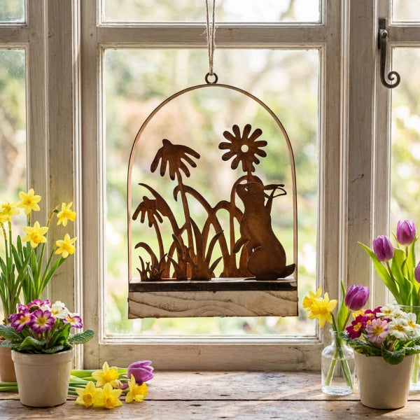Deko-Hänger Osterhase aus Metall mit Blumenmotiv im Holzrahmen vor einem Fenster mit Frühlingsblumen
