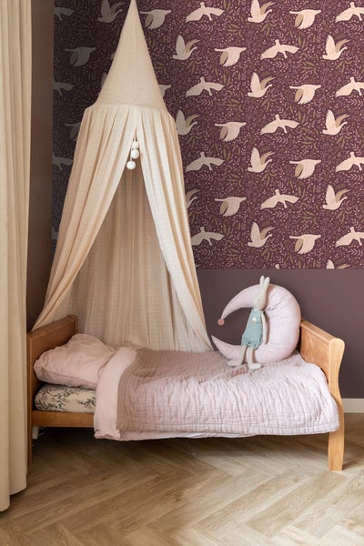 Kinderzimmer mit Himmelbett und Tapete mit Vogelmuster.