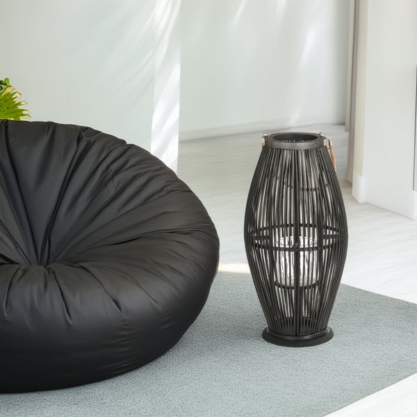 Helles Zimmer mit großem schwarzem Sitzsack und einer hohen dunklen Laterne aus Holz auf einem grauen Teppich.