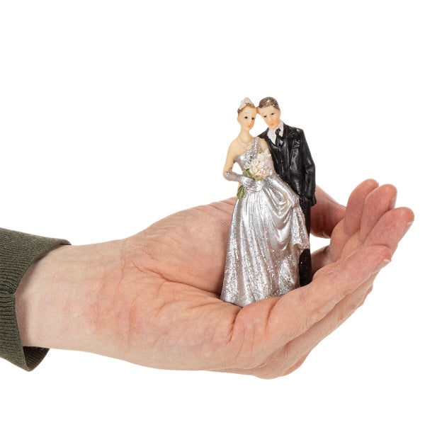 Kleine Hochzeitsfigur eines Brautpaars, zur Größenveranschaulichung in einer Hand gehalten.