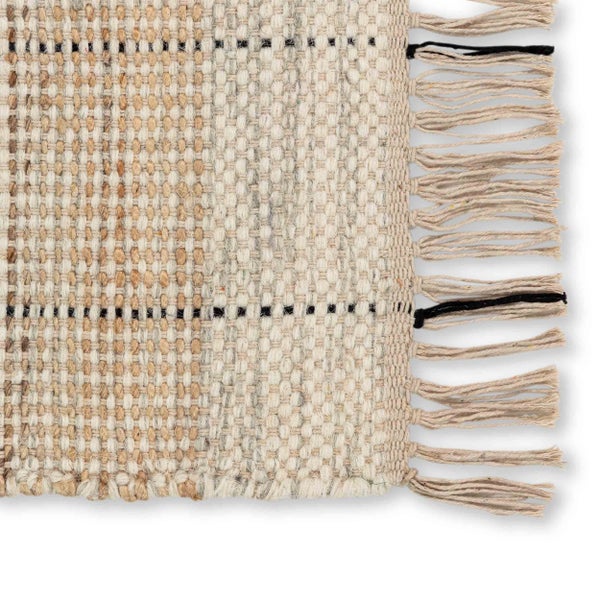 Nahaufnahme eines gewebten Teppichs mit Fransen, strukturierter Oberfläche und linearem Muster.