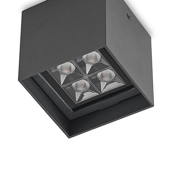 Moderne quadratische LED-Außen-Deckenleuchte in Schwarz mit goldfarbenem Reflektor, montiert an einer Holzdecke neben einer strukturierten Wand.