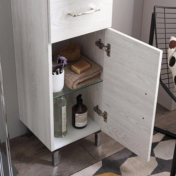 Moderner Bad-Seitenschrank in heller Holzoptik mit geöffneter Tür. Innen ein Glasfach mit Handtüchern, Seife und Kosmetikflaschen.