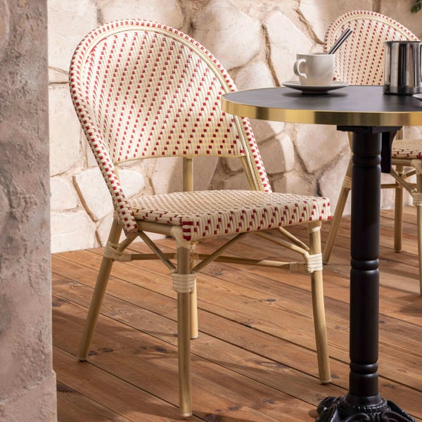 Bistrostuhl mit Geflecht in Cremeweiß und Rot, Holzgestell, auf einer Terrasse mit Holzboden und einem runden Tisch.