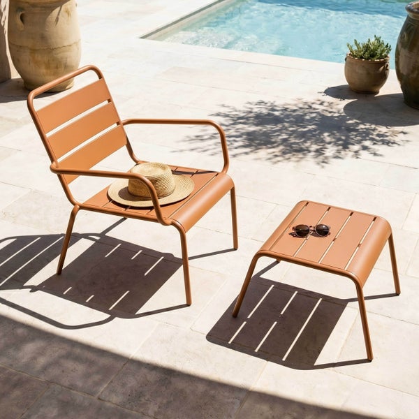 Moderner Gartenstuhl und Fusshocker aus Metall mit Lattendesign auf einer hellen Terrasse mit einer Sonnenbrille.
