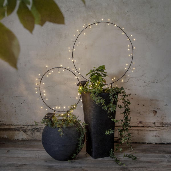 Dekorative Szene mit zwei Pflanzgefäßen und Solarleuchtenringen für den Garten