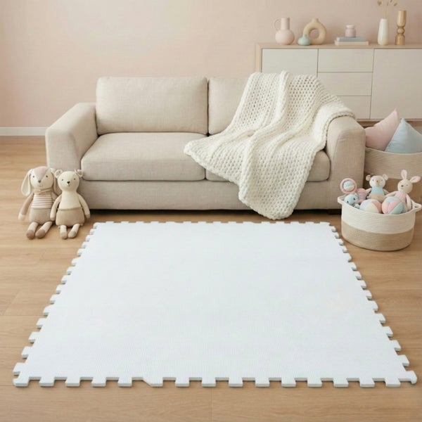 Weiße Schaumstoff-Puzzlematte auf hellem Holzboden in einem modern eingerichteten Wohnzimmer mit hellem Sofa und Spielzeug.