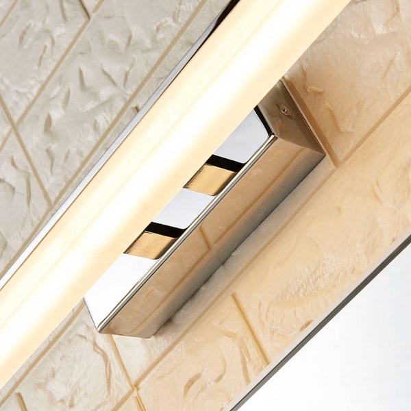 Nahaufnahme einer eingeschalteten LED-Wandleuchte mit verchromtem Gehäuse an einer strukturierten Wand.