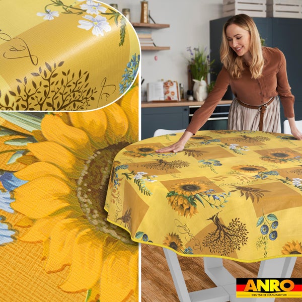 Frau breitet eine runde Tischdecke mit Sonnenblumenmuster in einer hellen, modernen Küche aus. ANRO Deutsche Manufaktur Logo.