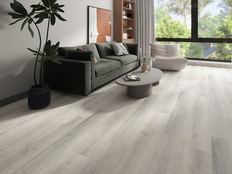 Helles Laminat in Holzoptik in einem modern eingerichteten Wohnzimmer mit dunklem Sofa und großen Fenstern.
