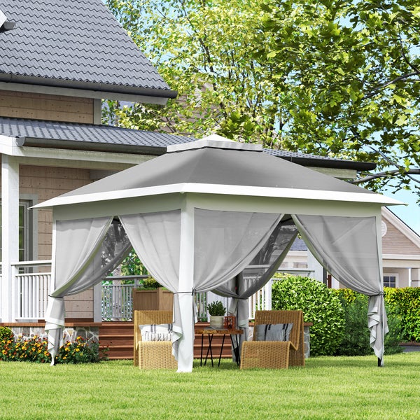 Moderner Gartenpavillon mit grauem Dach und hellen Vorhängen auf einer Rasenfläche vor einem Haus, inklusive Korbstühlen und Beistelltisch.