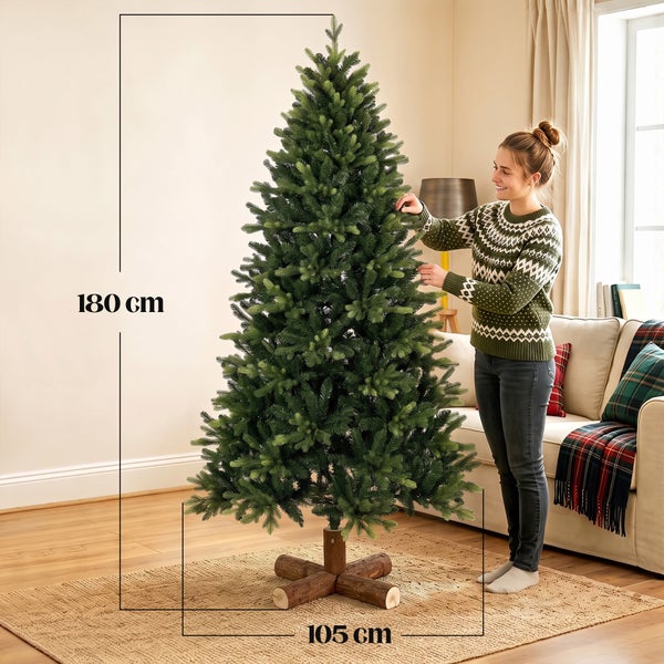 Ein künstlicher Weihnachtsbaum steht in einem hellen Wohnzimmer, dekoriert mit Geschenken auf dem Boden und weihnachtlicher Inneneinrichtung.