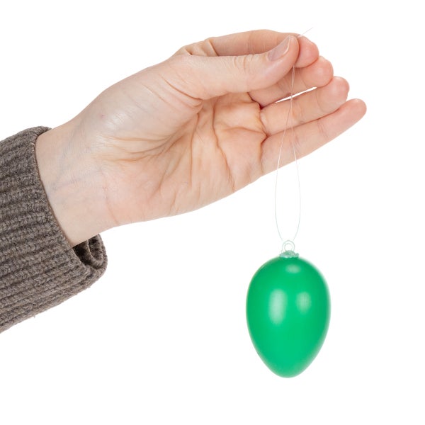 Eine Hand hält ein grünes Osterei mit Aufhänger.