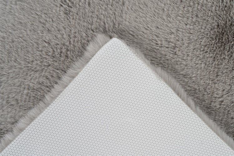 Nahaufnahme eines grauen Kunstfellteppichs mit rutschfester Unterseite.