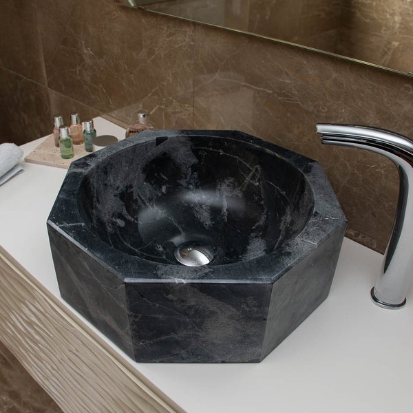 Achteckiges Aufsatzwaschbecken aus schwarzem Marmor auf einem hellen Waschtisch mit verchromter Armatur in einem modernen Badezimmer.