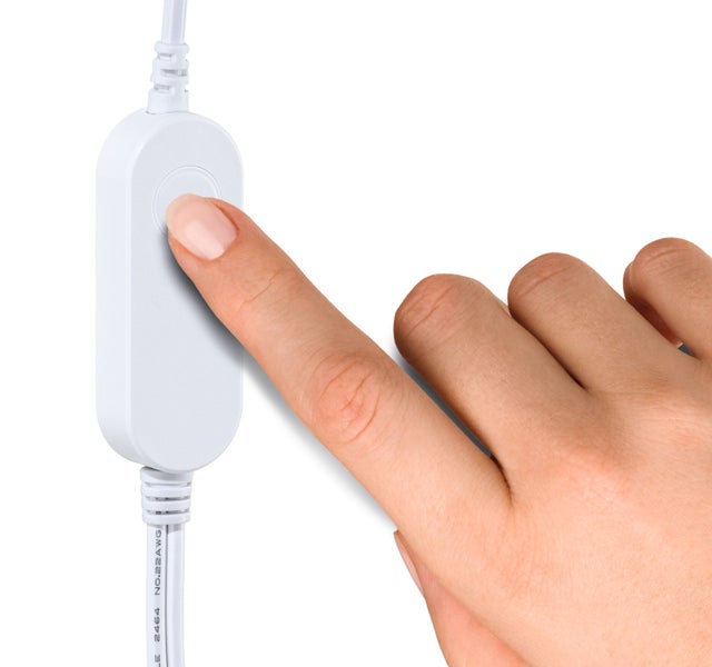 Eine Hand betätigt den runden Druckknopf eines weißen Schnurschalters an einem weißen Kabel.