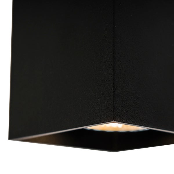 Detailansicht einer schwarzen, würfelförmigen Wandleuchte.