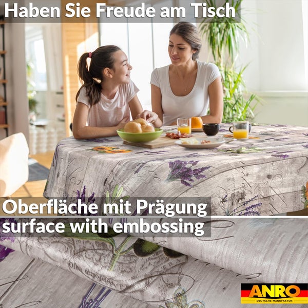 Runde Wachstuchtischdecke mit geprägter Oberfläche, Holzoptik, Lavendel- und Olivenmotiv. Mutter und Tochter am gedeckten Tisch. ANRO Logo.