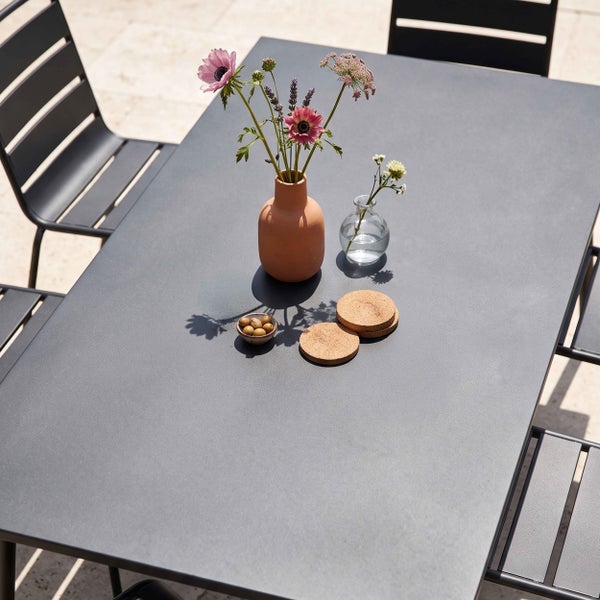 Moderner Gartentisch aus Metall mit passenden Gartenstühlen in Anthrazit auf einer hellen Terrasse.
