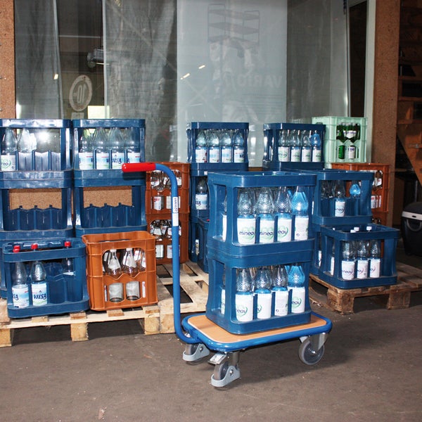 Getränkekisten mit Wasser auf einer Sackkarre und auf Paletten gestapelt
