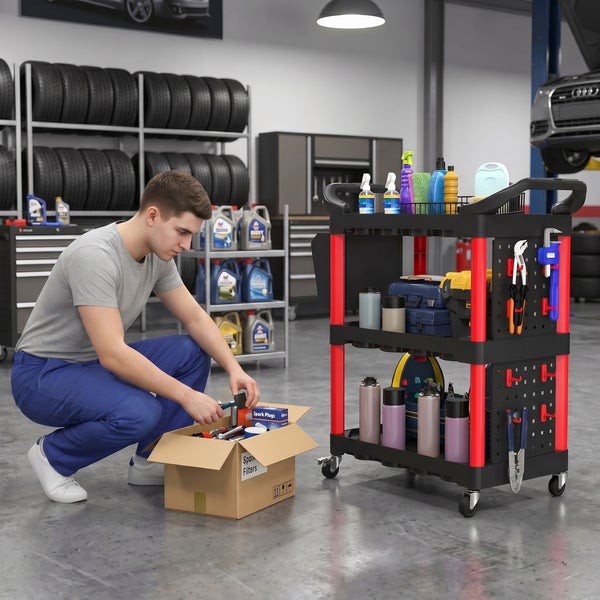 Kfz Mechaniker sortiert Zündkerzen aus einem Karton neben einem mobilen Werkstattwagen in einer professionellen Autowerkstatt mit Reifenregalen.