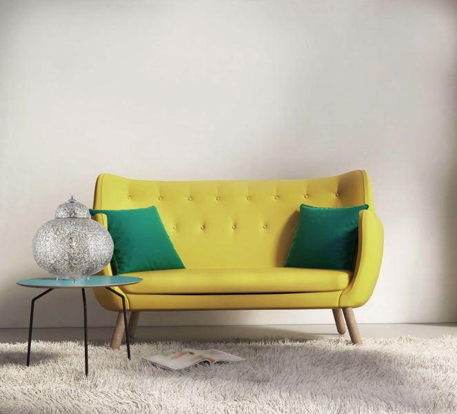 Gelbes Sofa mit grünen Kissen, Stehleuchte und Teppich