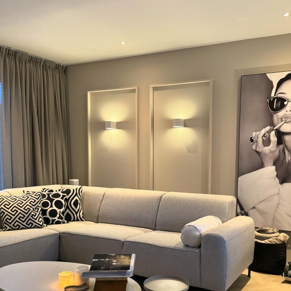 Wohnzimmer mit grauer Couch, Wandleuchten und dekorativer Kunst