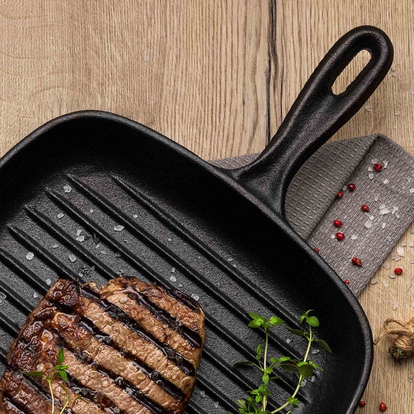 Grillpfanne mit Steak, Kräutern und Gewürzen auf Holztisch