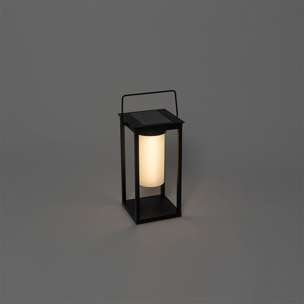 Beleuchtete schwarze Solar-Laterne aus Metall mit Tragegriff und Solarmodul.