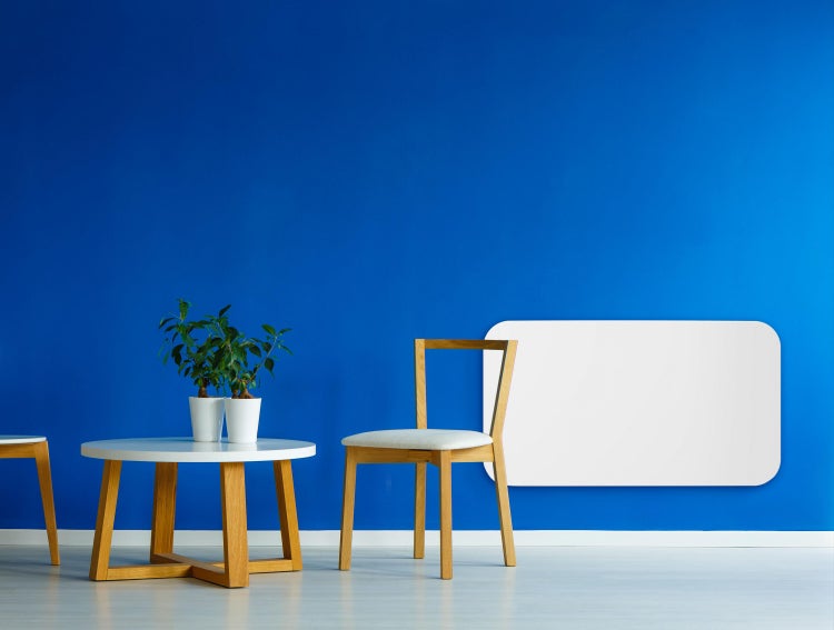 Helle, moderne Einrichtung mit Holzstühlen, runden Tischen und Zimmerpflanzen vor einer blauen Wand
