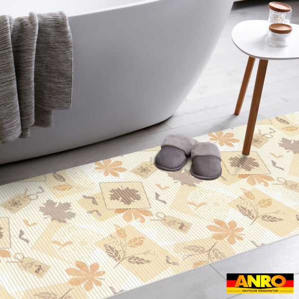 Gestreifter Badläufer mit herbstlichem Blattmuster vor einer weißen freistehenden Badewanne in einem hellen Badezimmer. ANRO Logo.