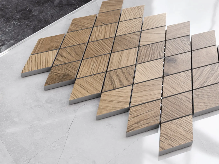 Mosaikfliesen in Rautenform mit Holzoptik-Maserung in Hellbraun auf einer grauen Fläche in Steinoptik.
