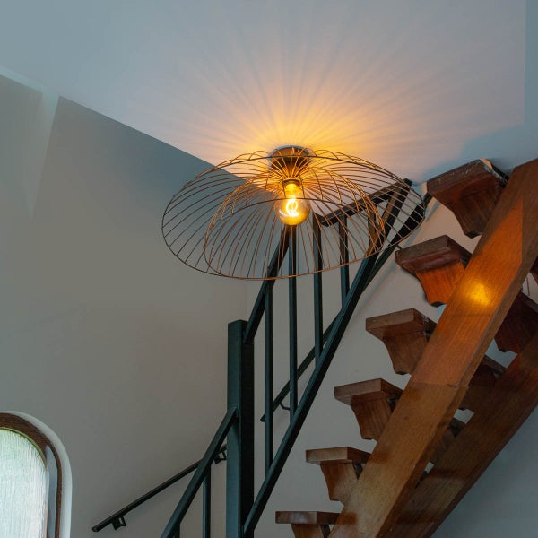 Szene mit einer Deckenleuchte mit Drahtschirm über einem Treppenhaus.