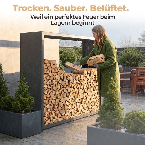 Frau stapelt Brennholz in ein großes, rechteckiges Kaminholzregal aus Metall auf einer Terrasse bei Regen.