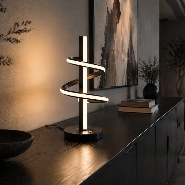 Moderne LED-Tischleuchte in Spiralform auf einem dunklen Sideboard aus Holz in einem organisierten Raum mit Wandbild.