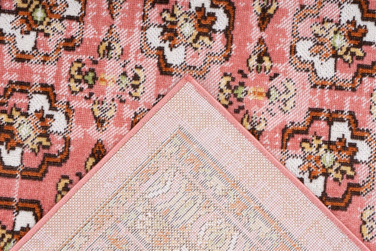 Nahaufnahme eines Teppichs mit orientalischem Blumenmuster, eine Ecke umgeklappt mit Ansicht der gewebten Rückseite.