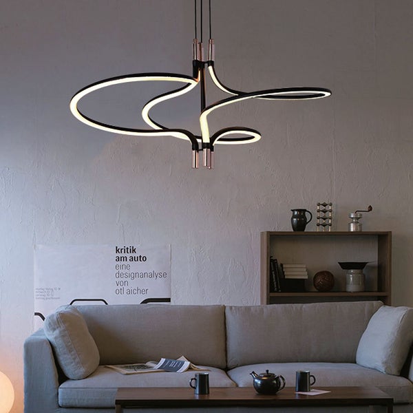 Moderne Pendelleuchte mit geschwungenem Design über einem Wohnzimmer.
