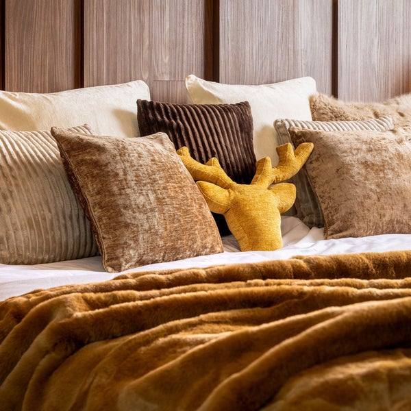 Dekorative Kissen und Decke auf einem Bett