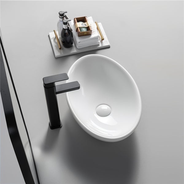 Modernes Badezimmer mit weißem ovalem Aufsatzwaschbecken aus Keramik, schwarzer Waschtischarmatur und Zubehör auf einem Tablett.