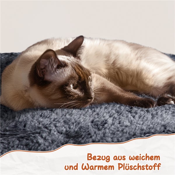 Eine Siamkatze liegt auf einem grauen Plüschtierbett.