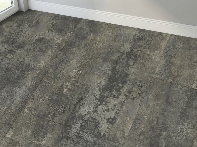 Vinylboden in Fliesenoptik mit rustikaler Betonstruktur in einem Raum mit weißer Fußleiste.